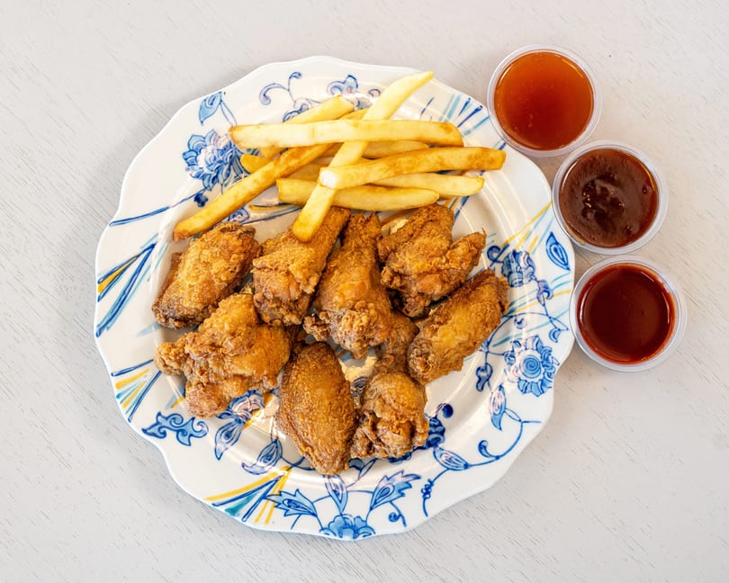 Crispy fried chicken wings and golden french fries on a decorative plate with three dipping sauces.
